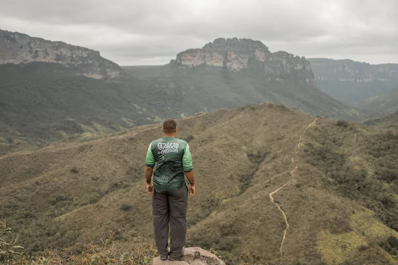 Guia da Coração da Chapada contemplando o Vale do Pati, com a trilha ao longe e o Morro do Castelo ao fundo